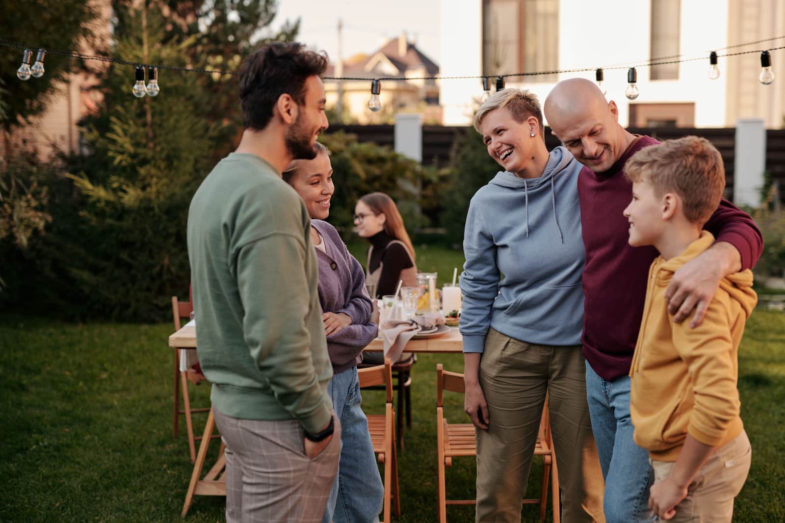 Family laughing together at a backyard picnic under string lights