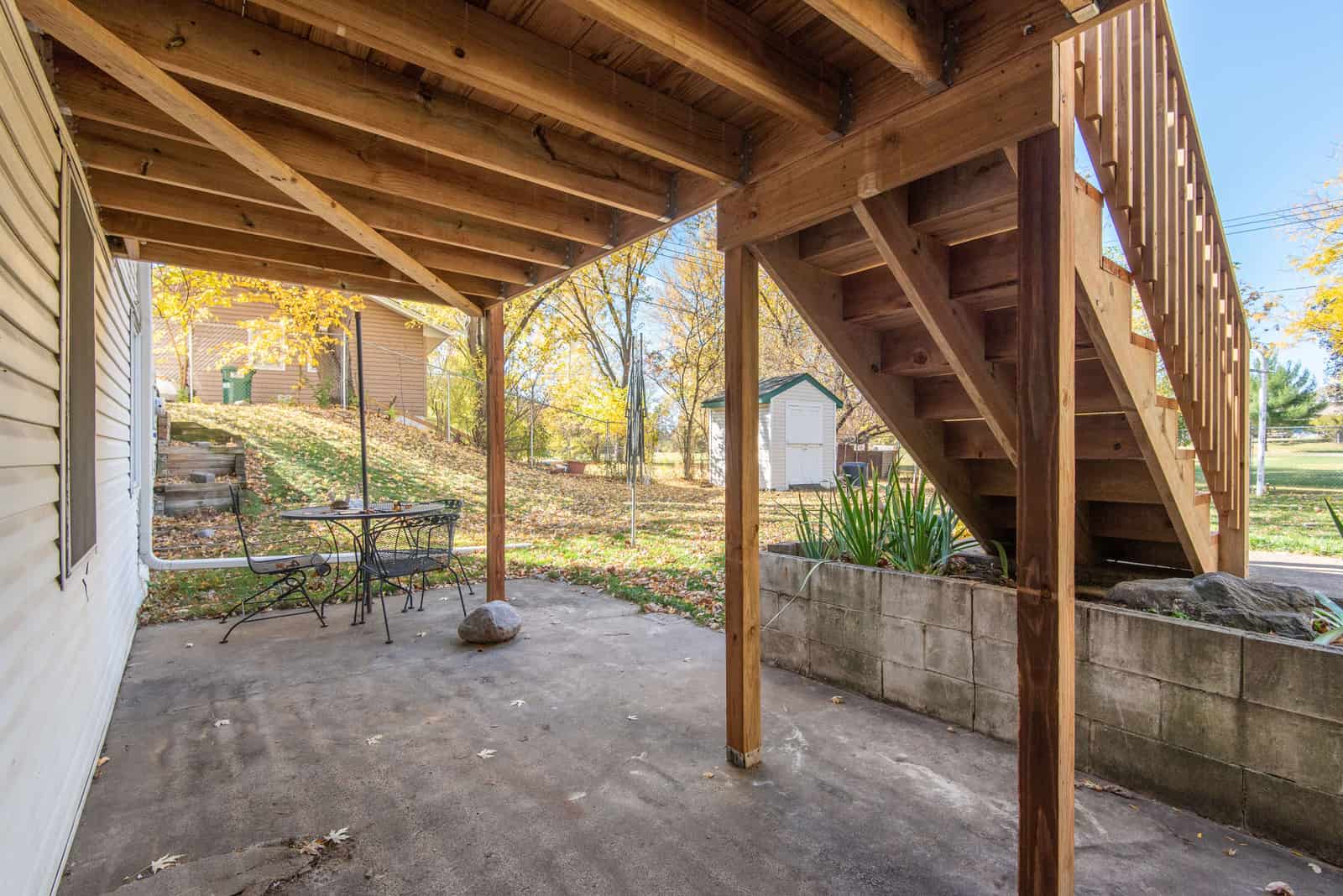 Wooden staircase leading down to a backyard patio