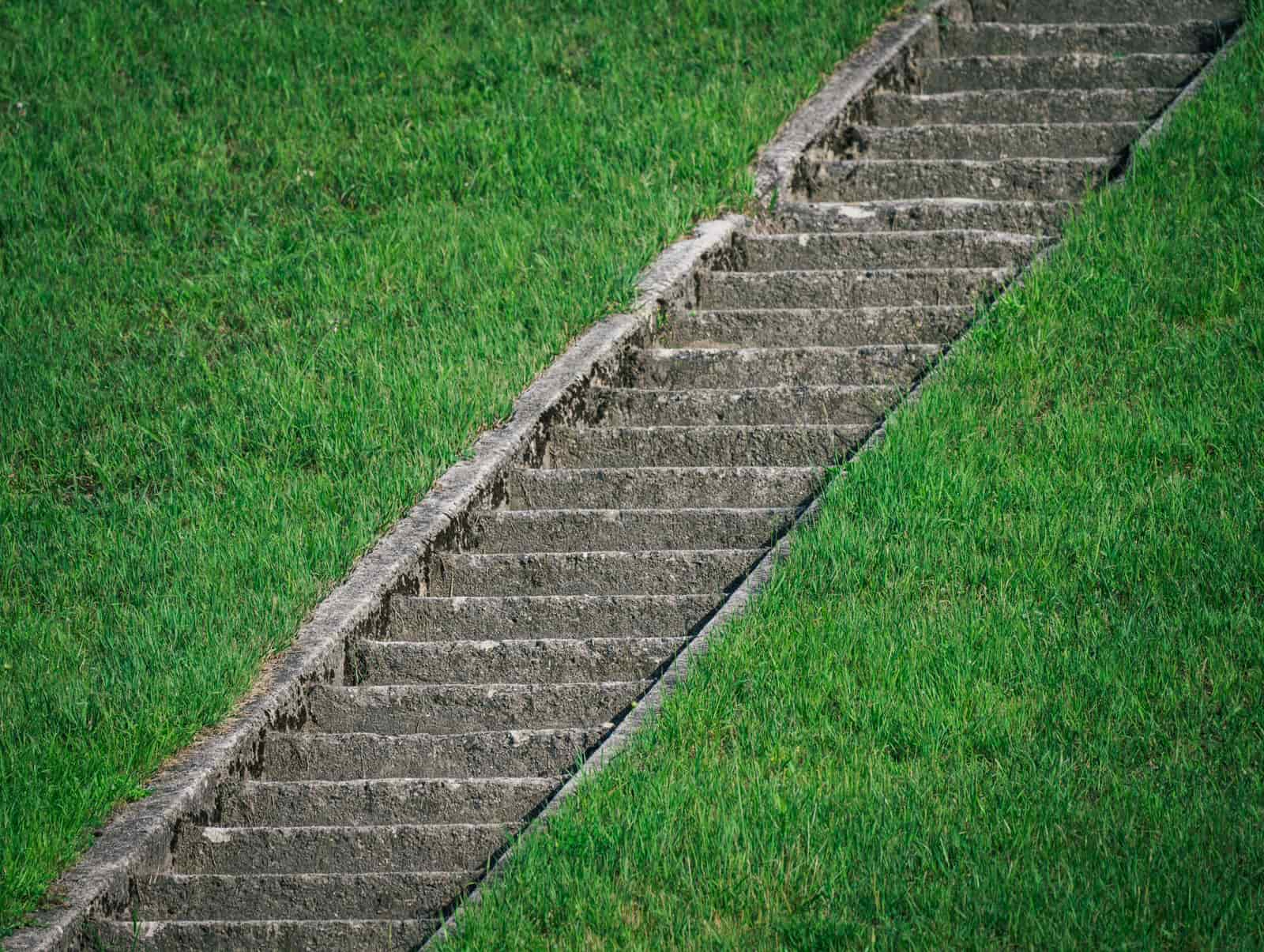Concrete steps cut diagonally into a steep grass slope