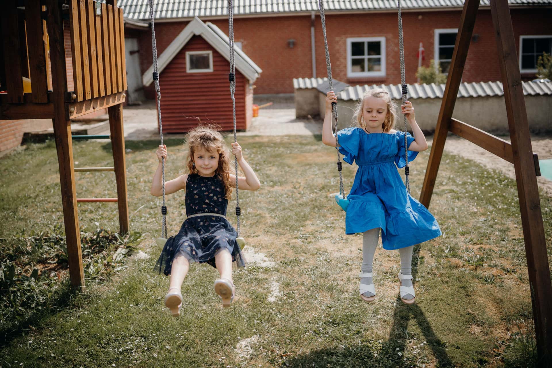 Two girls on the swings of a sunny backyard swing set