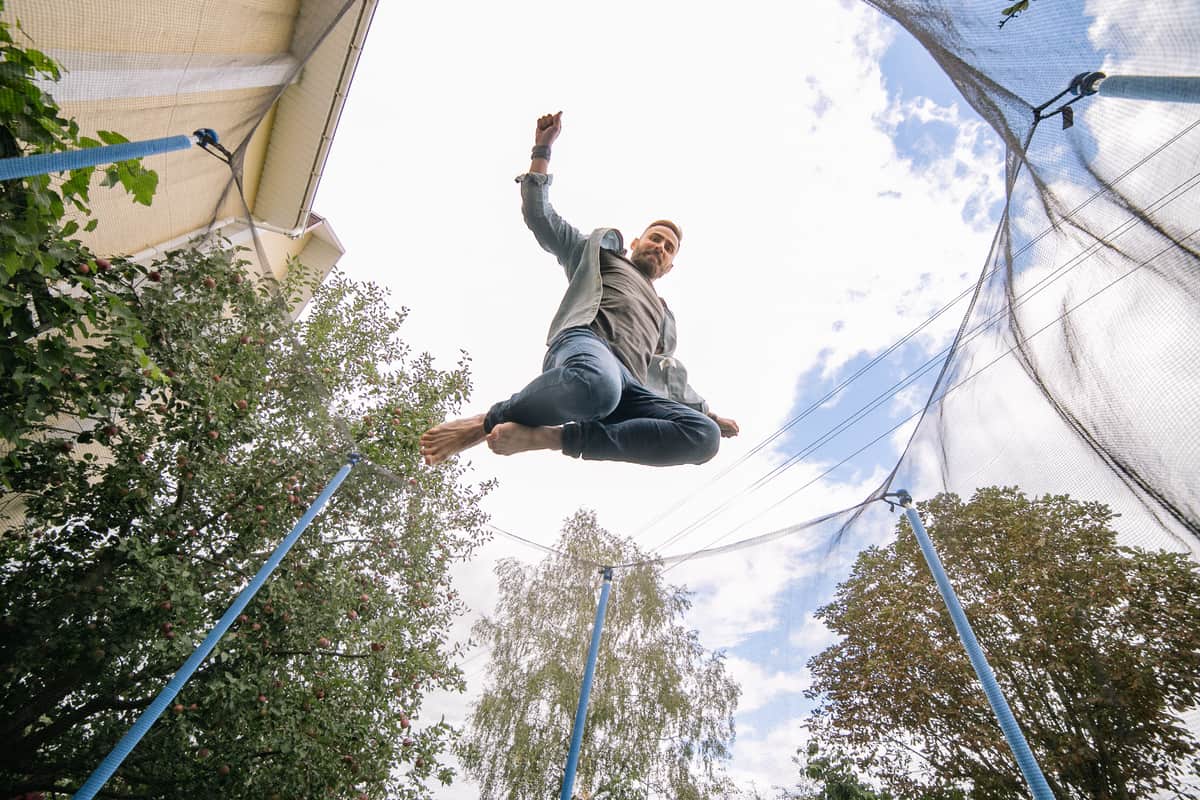Man jumping on an outdoor trampoline under a clear sky